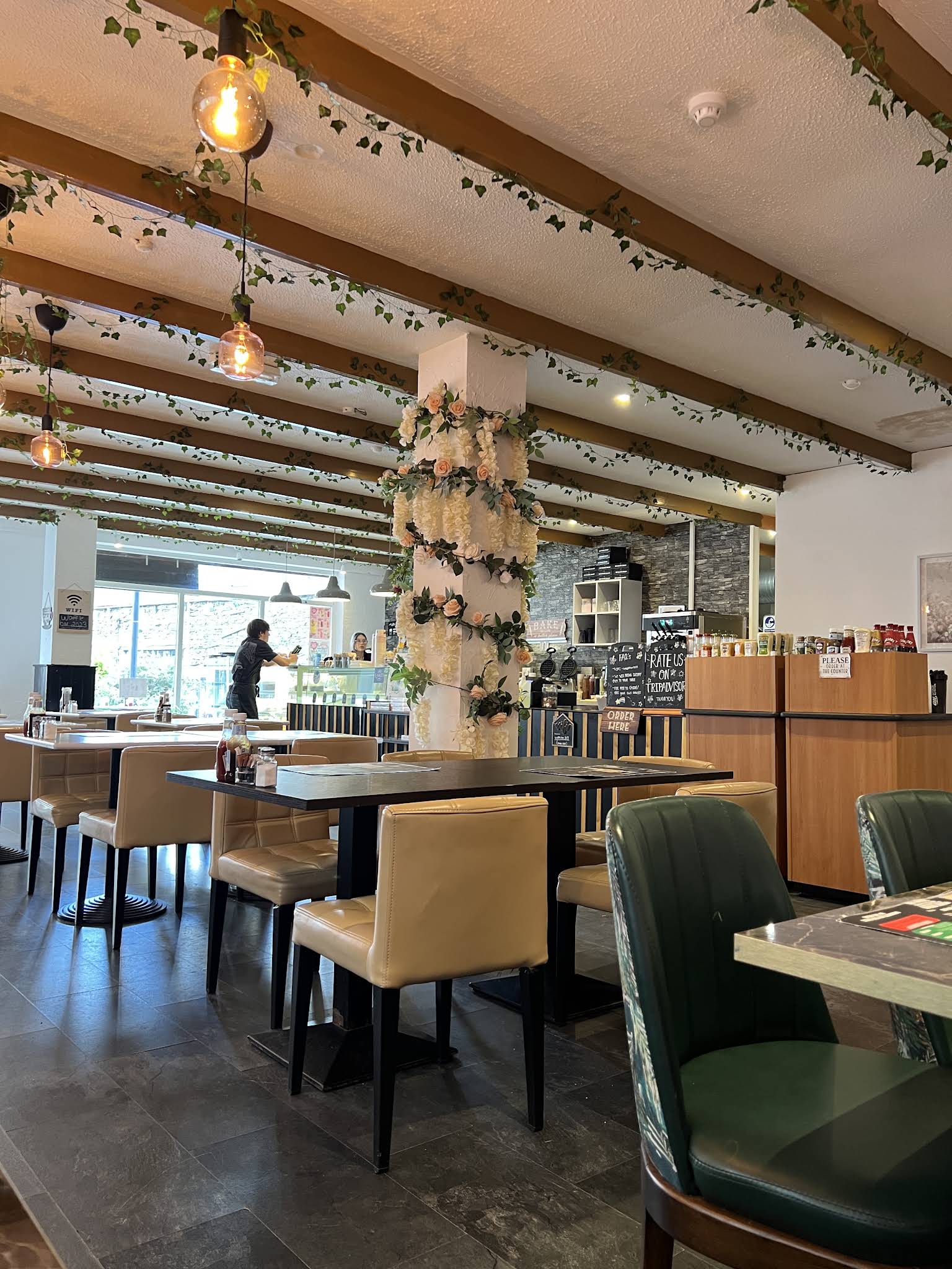 Waffleicious dining room with a flower-covered pillar, timber ceiling beams, hanging lights and café tables